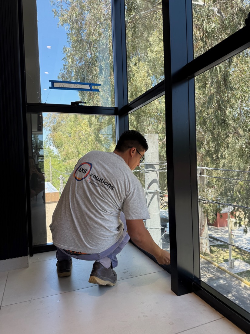 Personal de AXS Solutions realizando limpieza de detalle en ventana